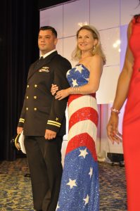 Woman in American flag inspired gown stands next to a man in pilot uniform.