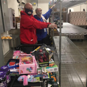 Two volunteers at Akron House sorting donated goods onto shelves