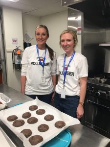 Two volunteers wearing matching shirts baking fresh cookies in the Akron house kitchen