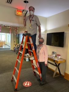 Volunteer supporting another volunteer on a ladder as he replaces a light bulb at Cleveland House