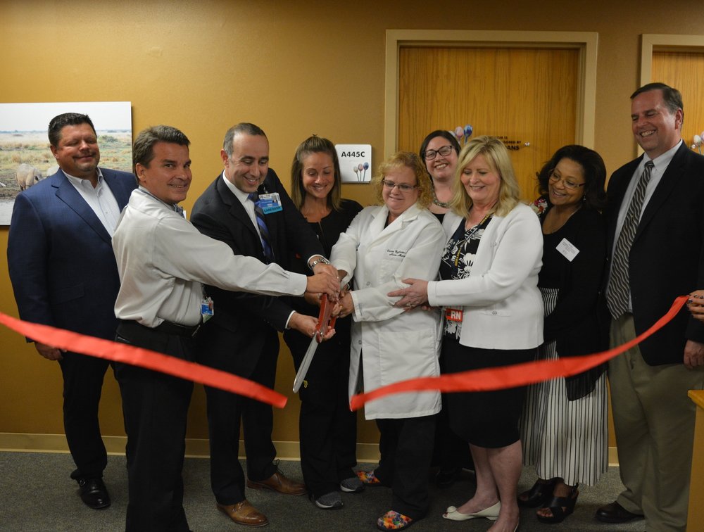 A group of people smiling and cutting a ribbon