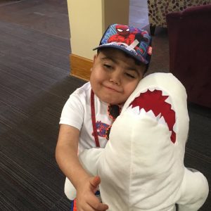 Child holding large shark plush