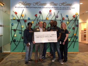 National General Check Presentation group stands in front of a backdrop holding a giant check.