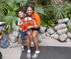 mom and son smiling for photo in rainforest at zoo exhibit