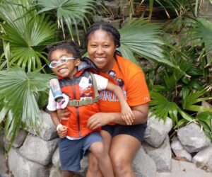 mom and son smiling for photo in rainforest at zoo exhibit