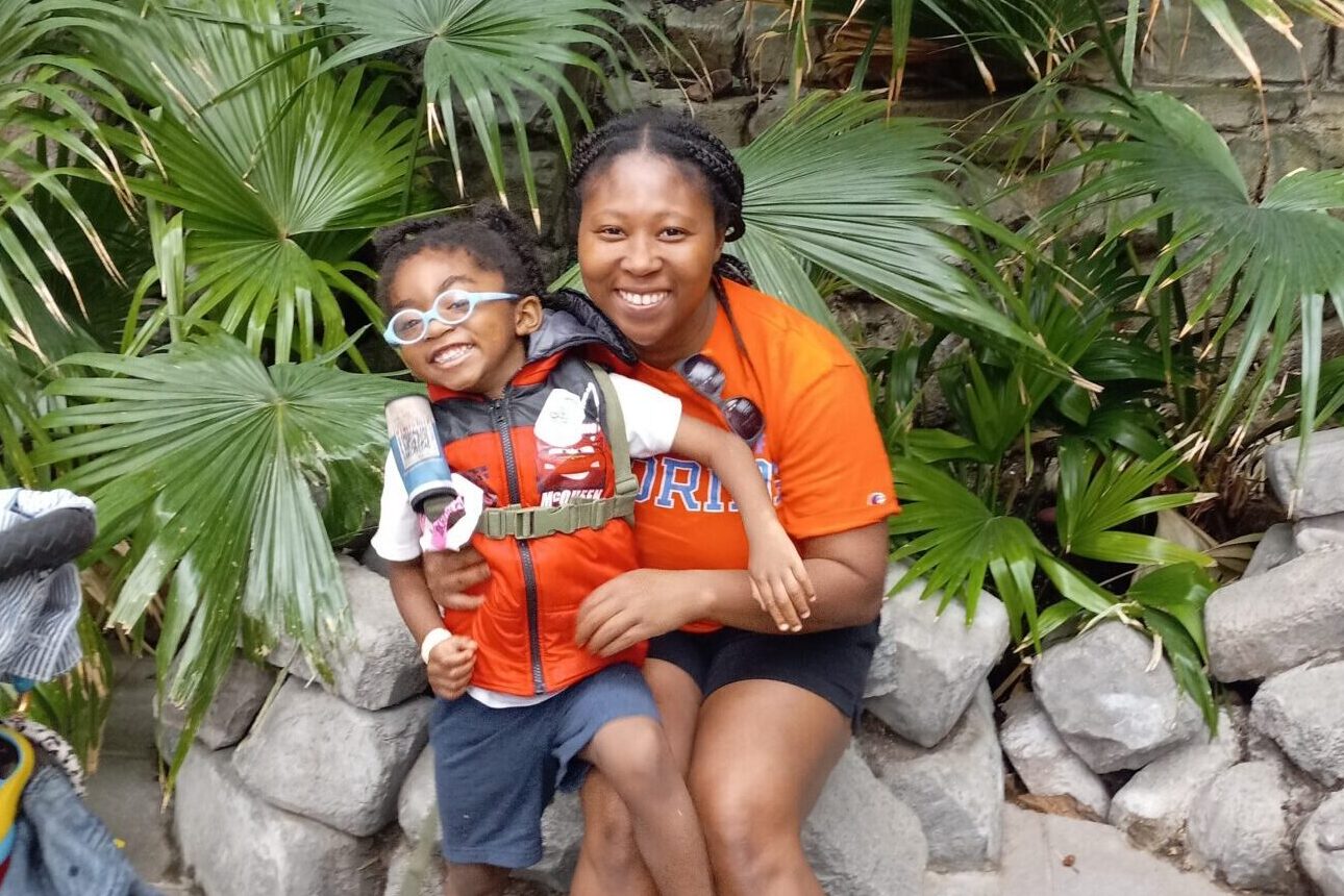 mom and son smiling for photo in rainforest at zoo exhibit