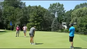 Four people on putting green.