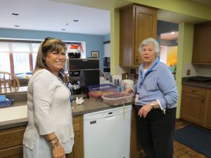 Two women in a kitchen by dishwasher