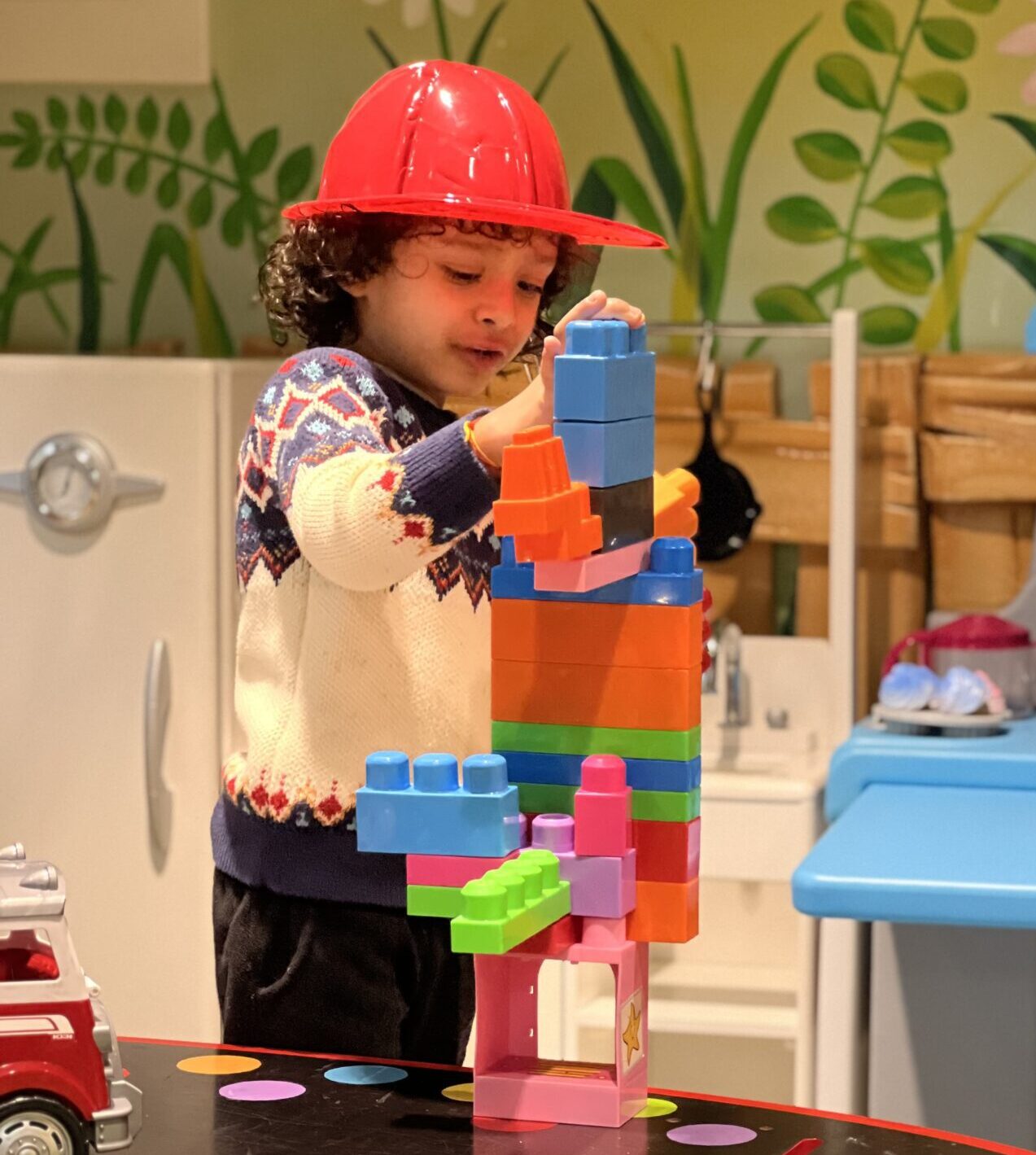 little boy with hard hat building tower out of blocks.