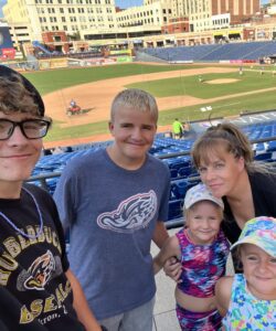 two teenage boys with mom and two young girls at a ballpark