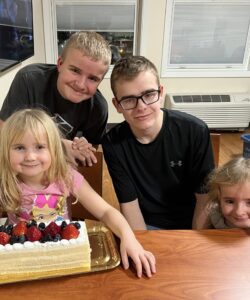 Girl with decorated cake and three children at table