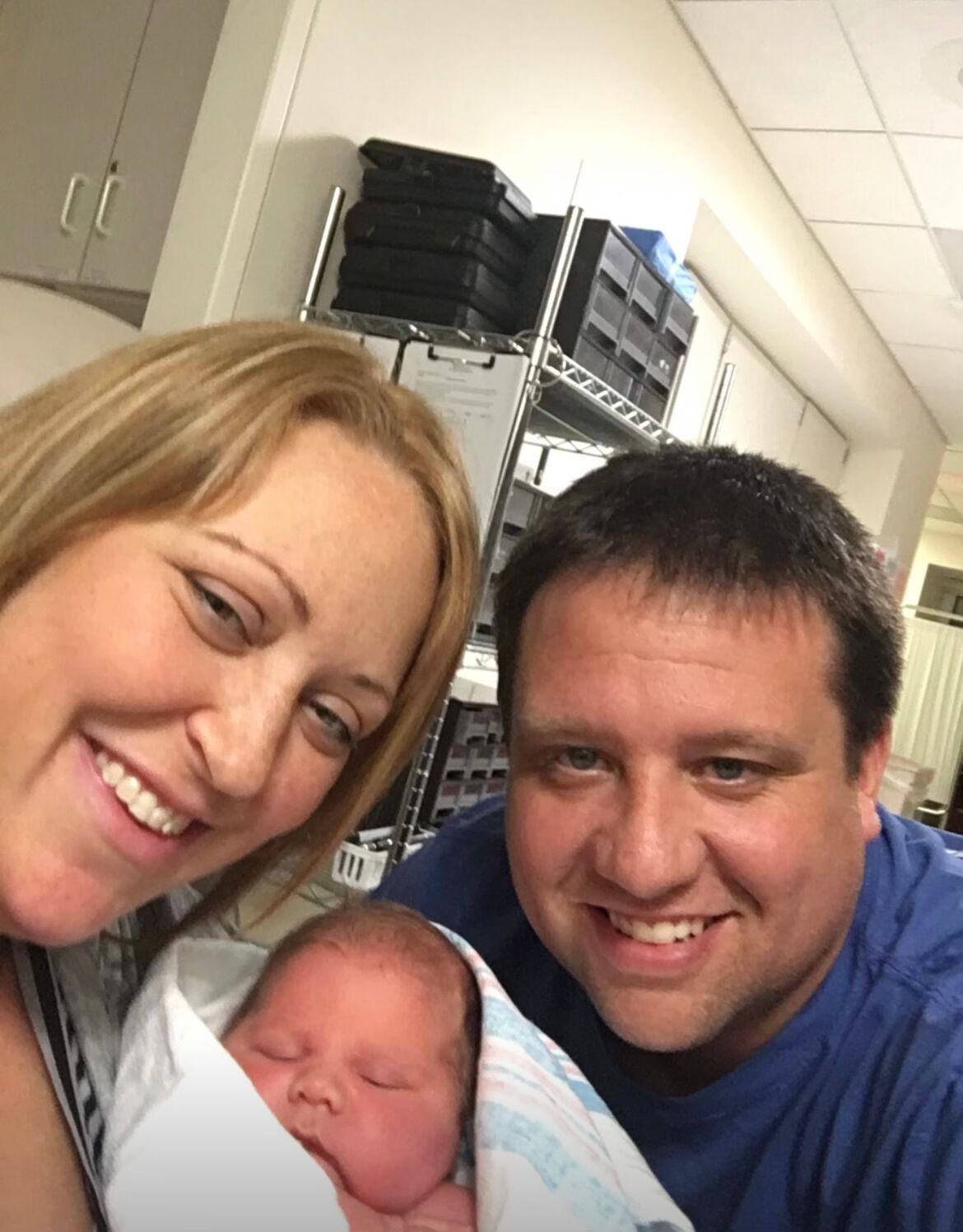 Two parents hold newborn baby in hospital