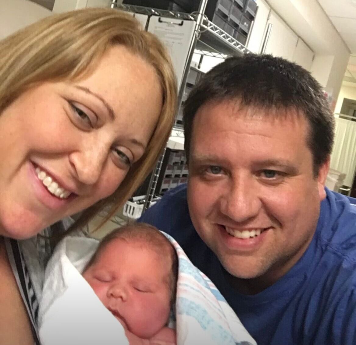 Woman, baby, man posing for a selfie in hospital