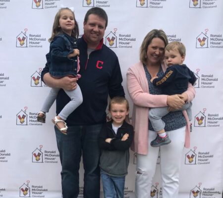 Family of 5 pose for photo against backdrop