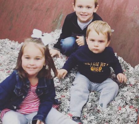 Three children in recycling bin of pull tabs