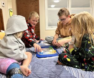 Four children playing a game on a bed