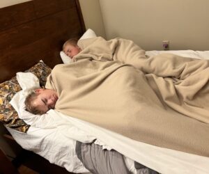 Two boys sleeping in bed with blankets