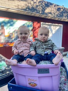 two little boys sitting on bucket of pull tabs