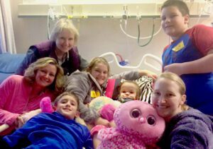 Two-year-old Shae in a hospital bed, surrounded by her family.
