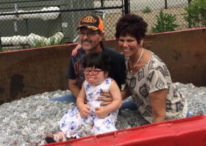 three individuals posing for photo in a full recycling container