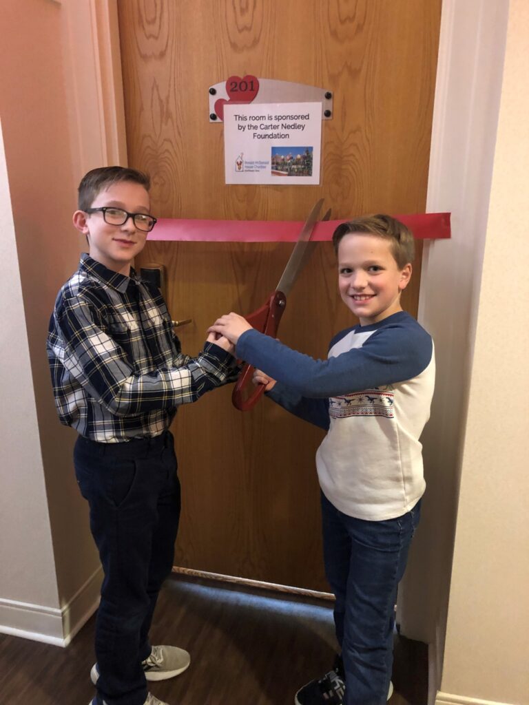 Nedley boys smiling while cutting a ribbon