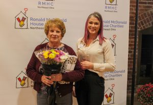 Two women, one with flowers, posing in front of a backdrop