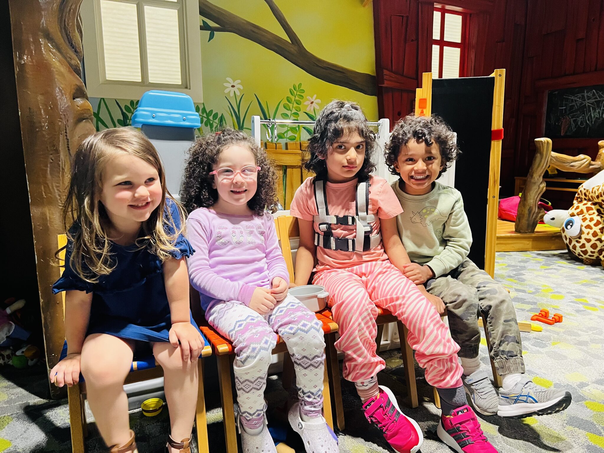 four kids smiling for a photo in a playroom